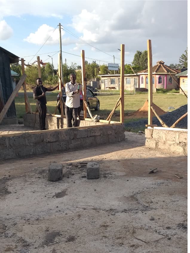 Two men standing behind a stone foundation wall set with upright timber posts