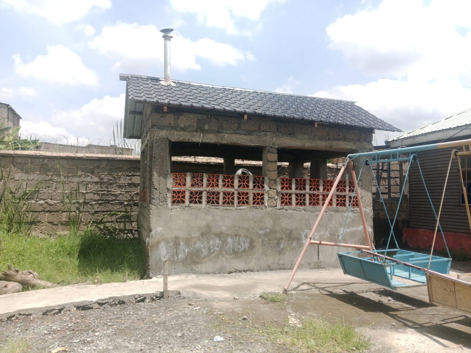 The finished kitchen — plastered walls, a tiled roof and a chimney, standing in the school yard