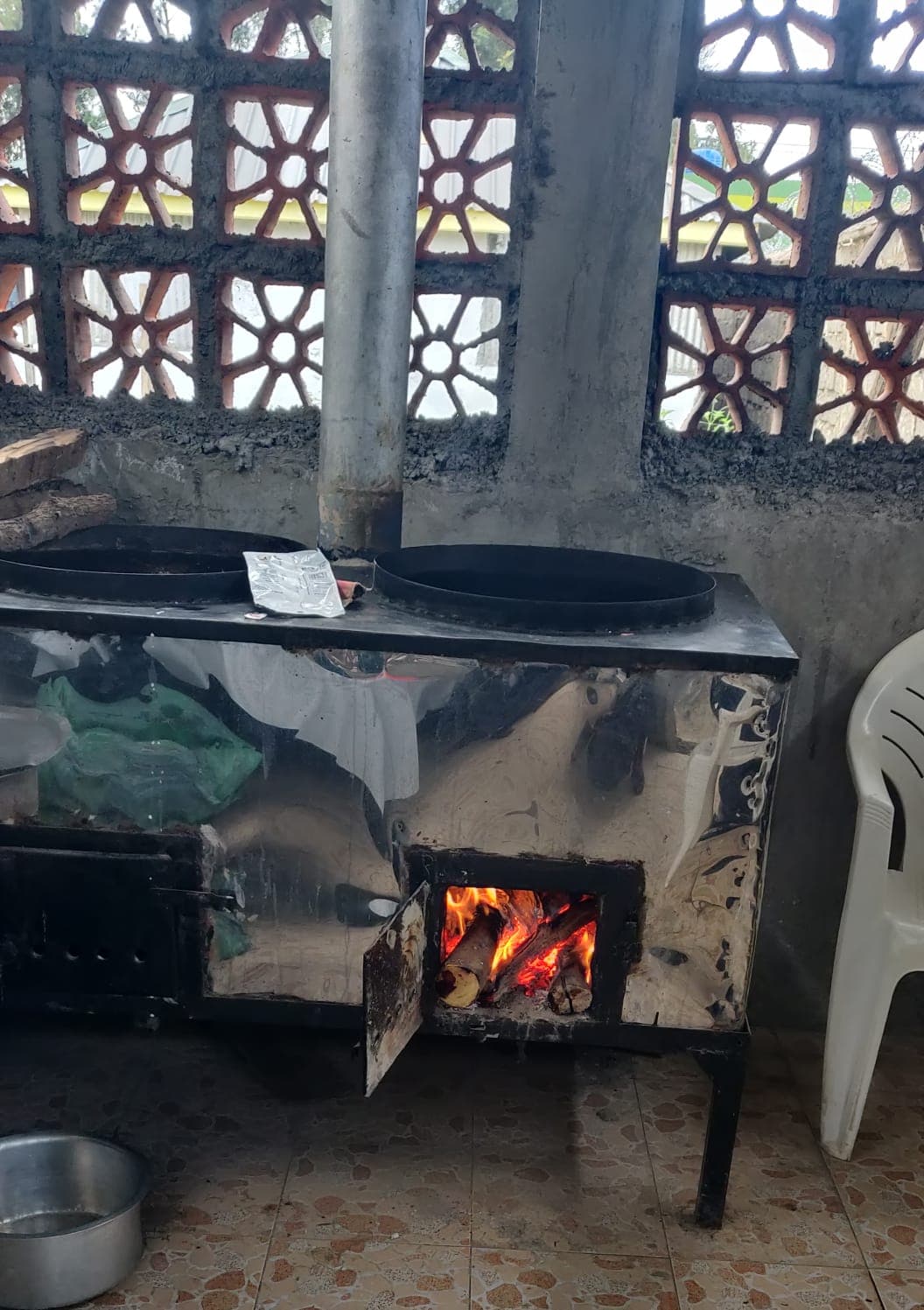 A wood fire burning in the new jiko, a pot on the plate above it